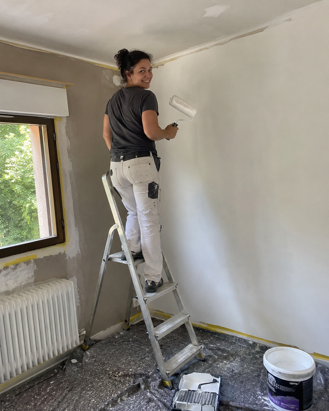 Peintre en bâtiment sur un escabeau, rouleau à la main